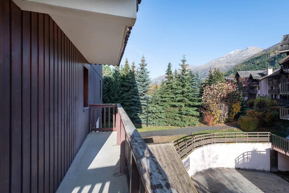 Balcon de l’appartement donnant sur les sapins, les chalets voisins et les sommets de la vallée