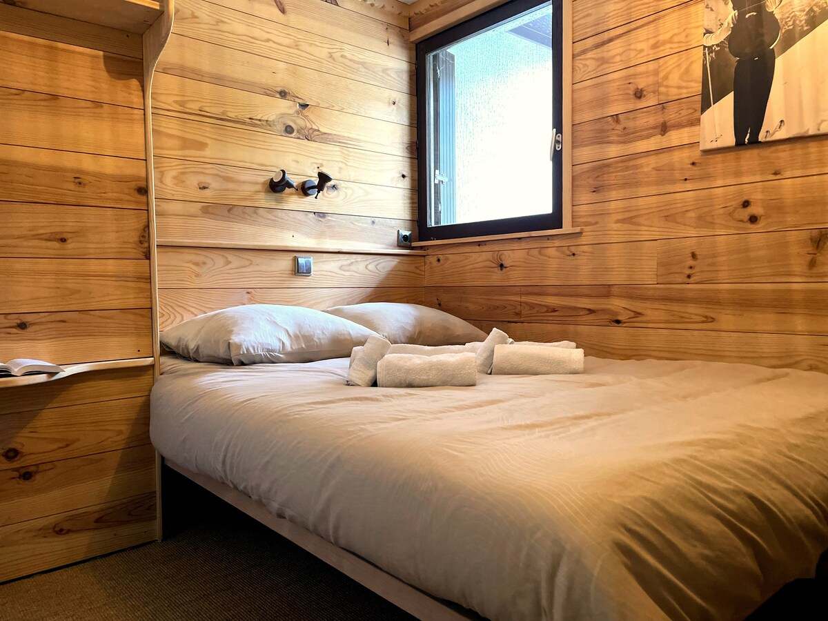 Chambre avec lit double, lambris de mélèze clair et linge de lit blanc, appartement à Serre Chevalier