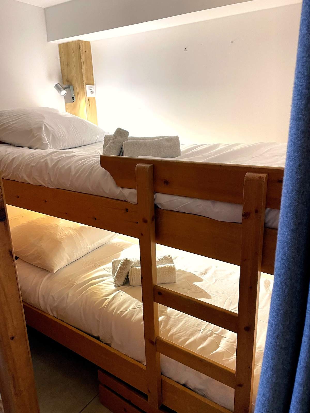 Lits superposés en bois avec linge blanc et serviettes roulées, chambre enfants de l’appartement à Serre Chevalier