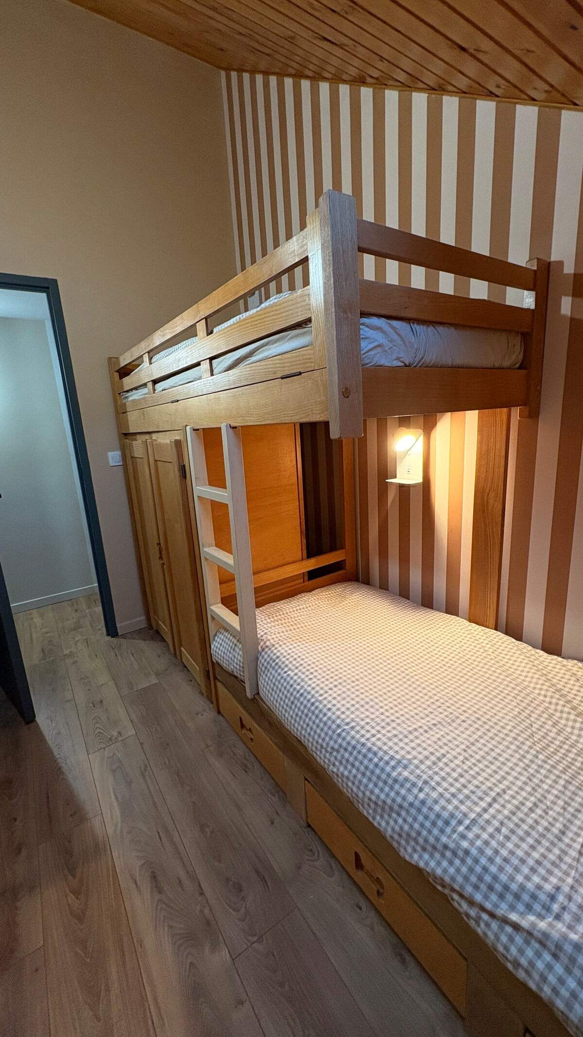 Chambre enfants avec lits superposés en bois, tiroirs de rangement et papier peint à rayures