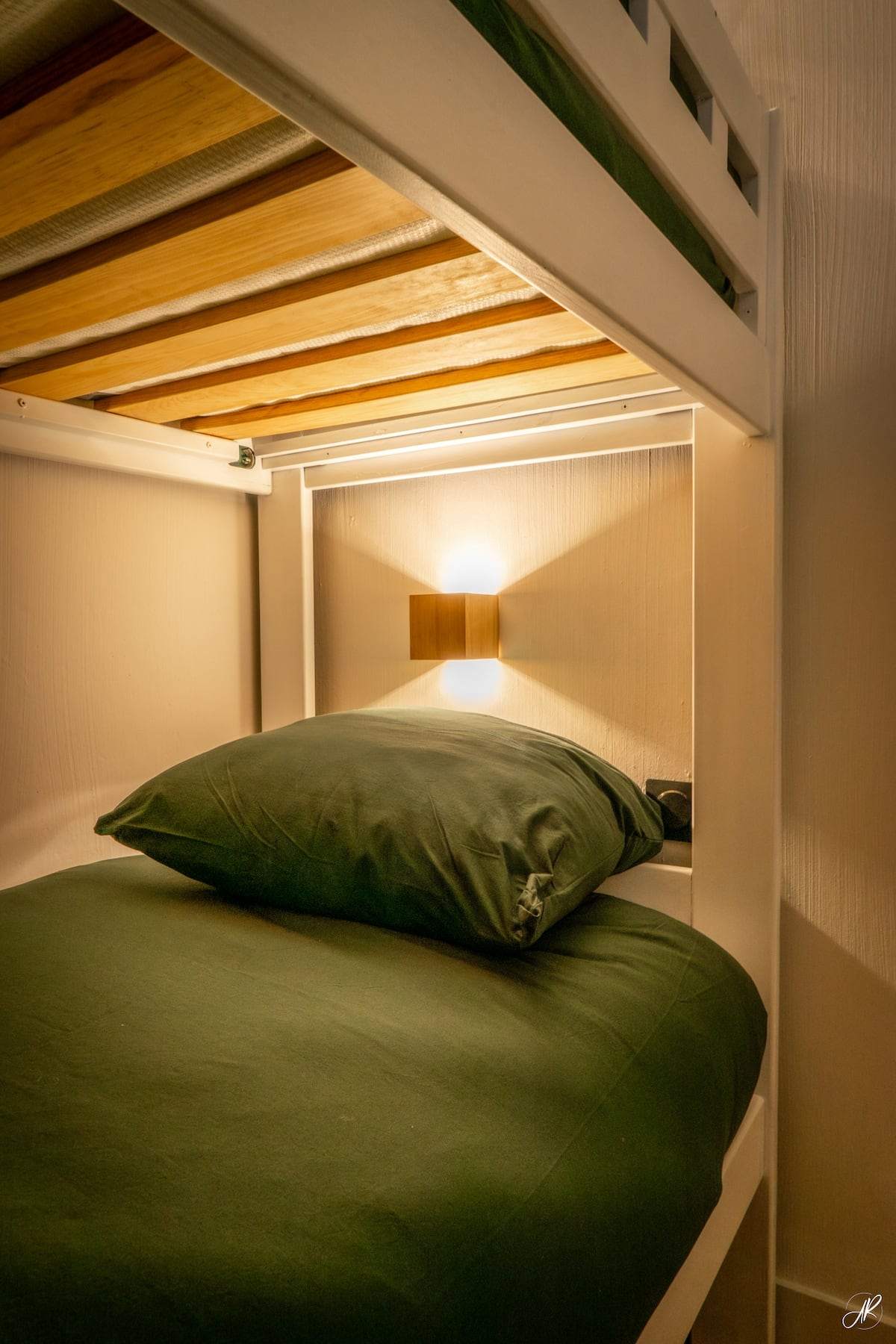 Coin montagne pour les enfants : lit superposé en alcôve, linge vert et applique de lecture