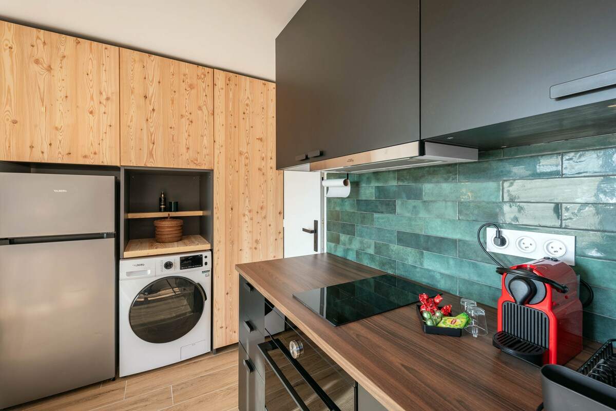 Rangements en bois clair, réfrigérateur, lave-linge intégré et plan de travail en noyer de la cuisine