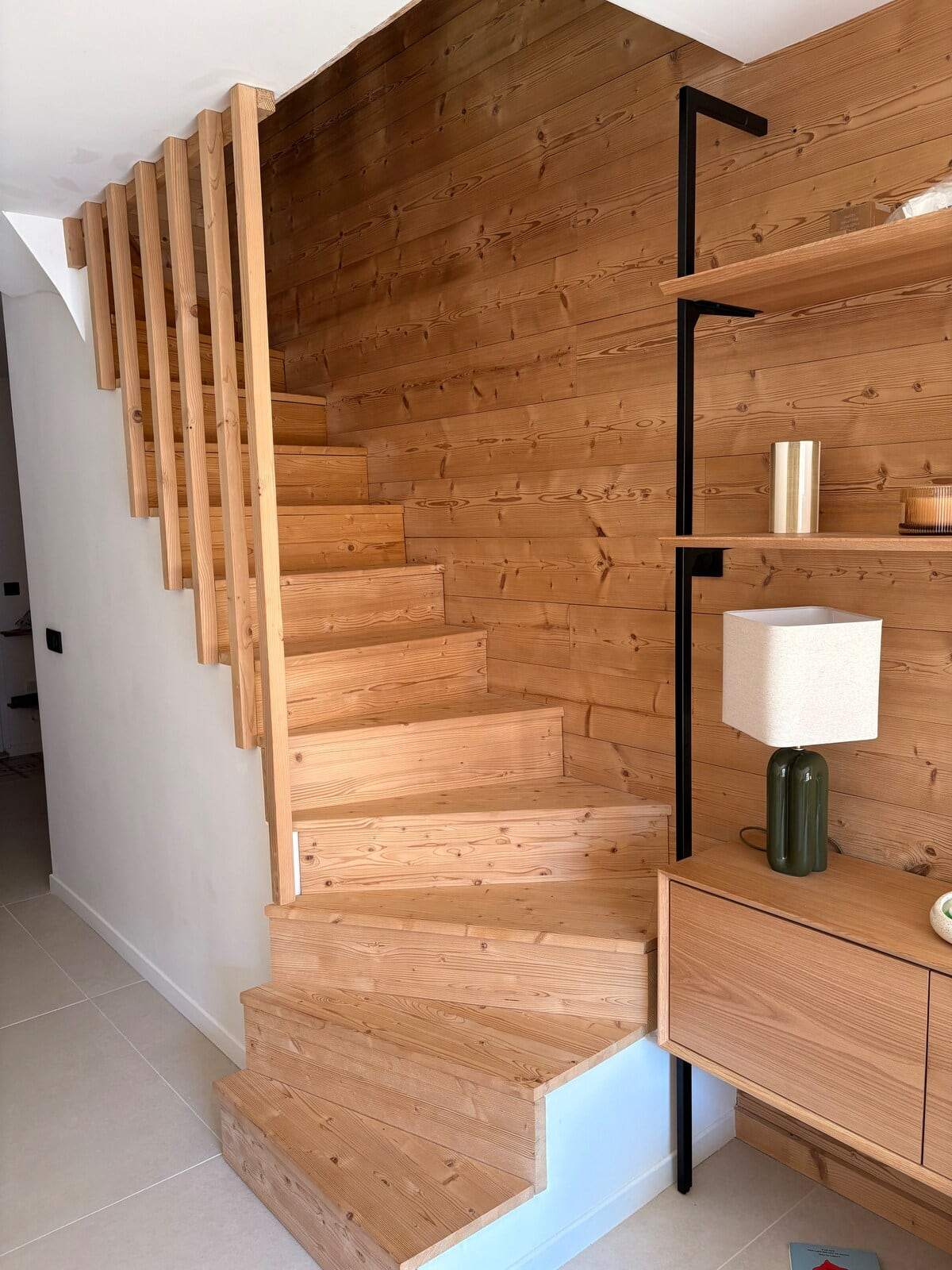 Escalier en bois massif desservant les trois niveaux du triplex, avec rangements intégrés