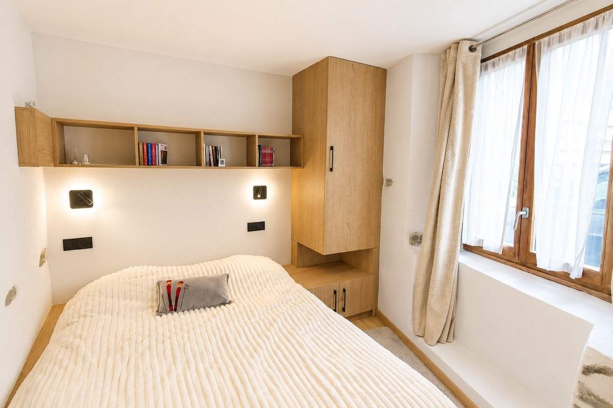 Lit intégré avec étagère bibliothèque, penderie sur mesure et fenêtre sur la rue du village