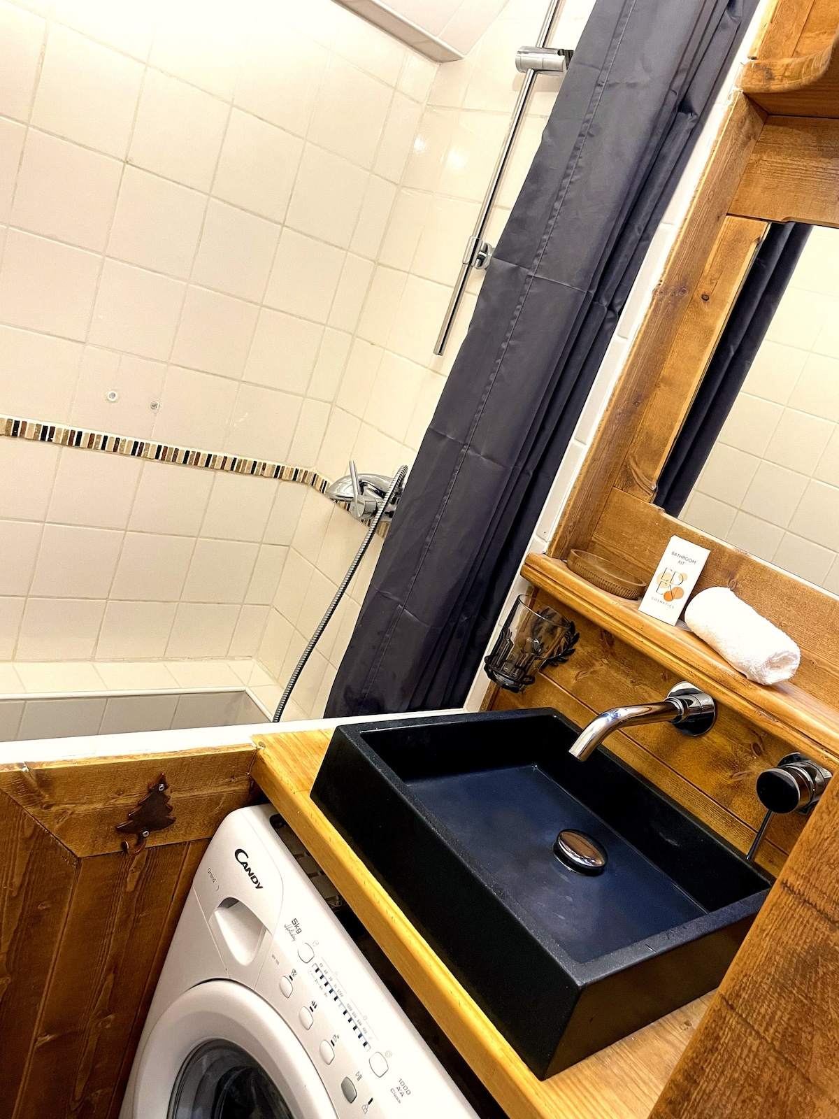 Seconde salle de bain avec douche, vasque en pierre noire, miroir en bois et lave-linge, appartement à Serre Chevalier
