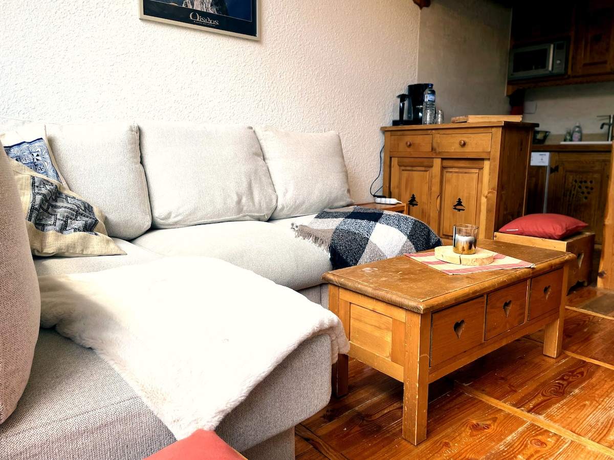 Coin salon cosy avec plaid à carreaux, table basse en bois sculpté et coussins, ambiance chalet à Serre Chevalier
