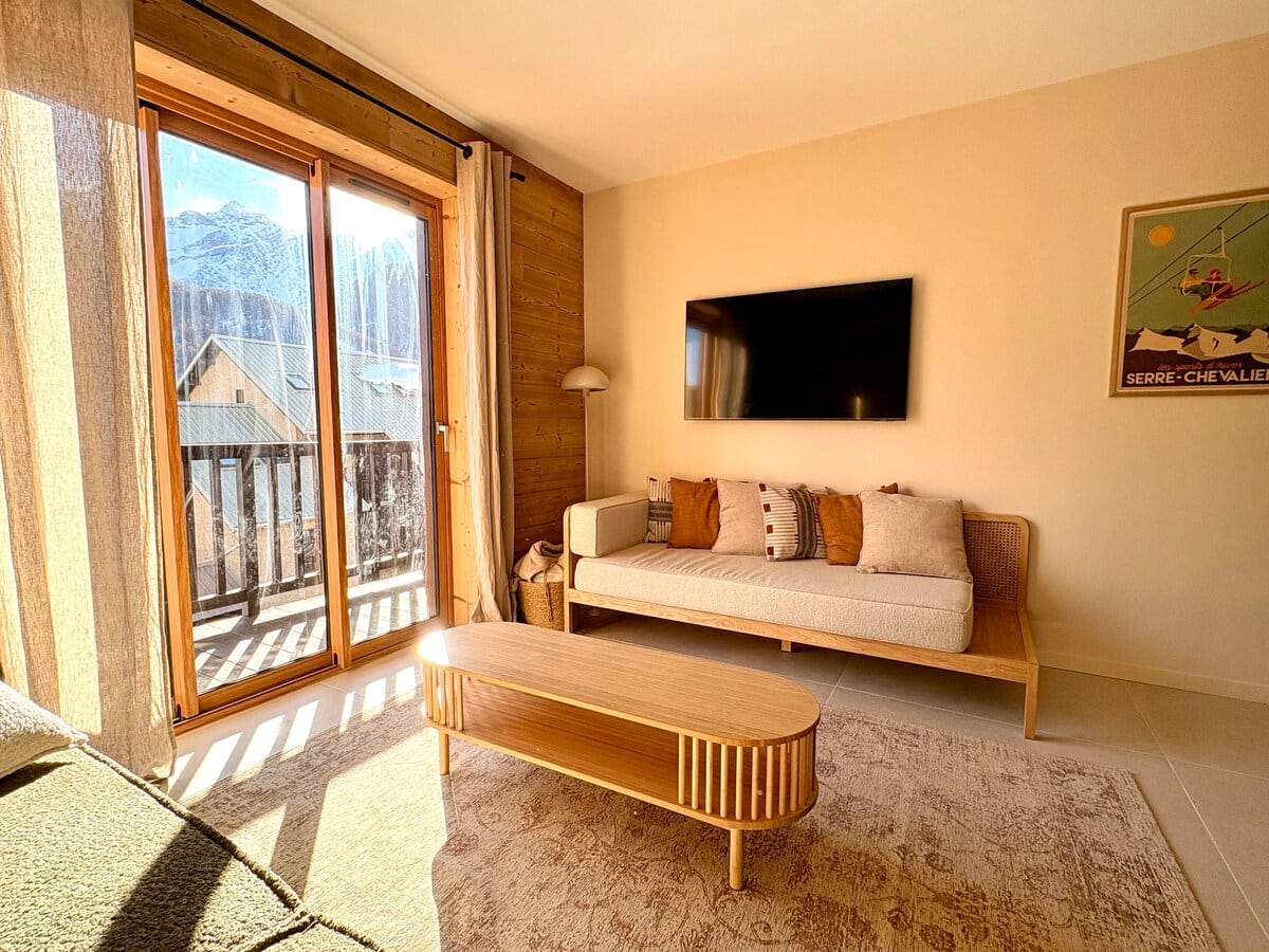 Coin salon avec banquette, télévision murale et affiche vintage Serre Chevalier