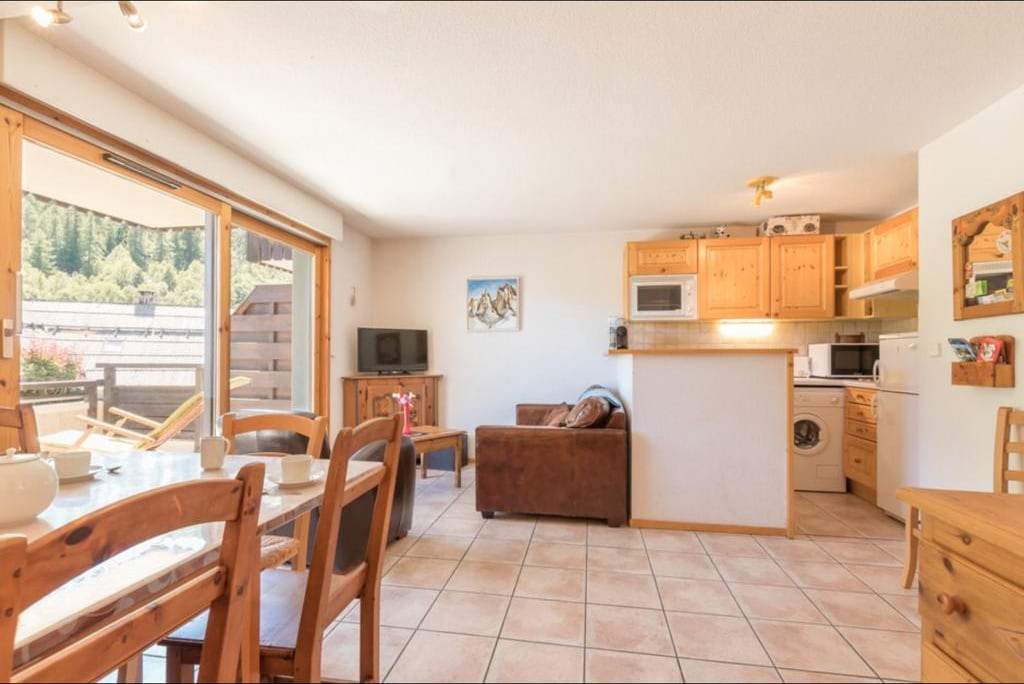 Vue d’ensemble du séjour et de la cuisine ouverte, sol carrelé, meubles en pin et accès direct à la terrasse