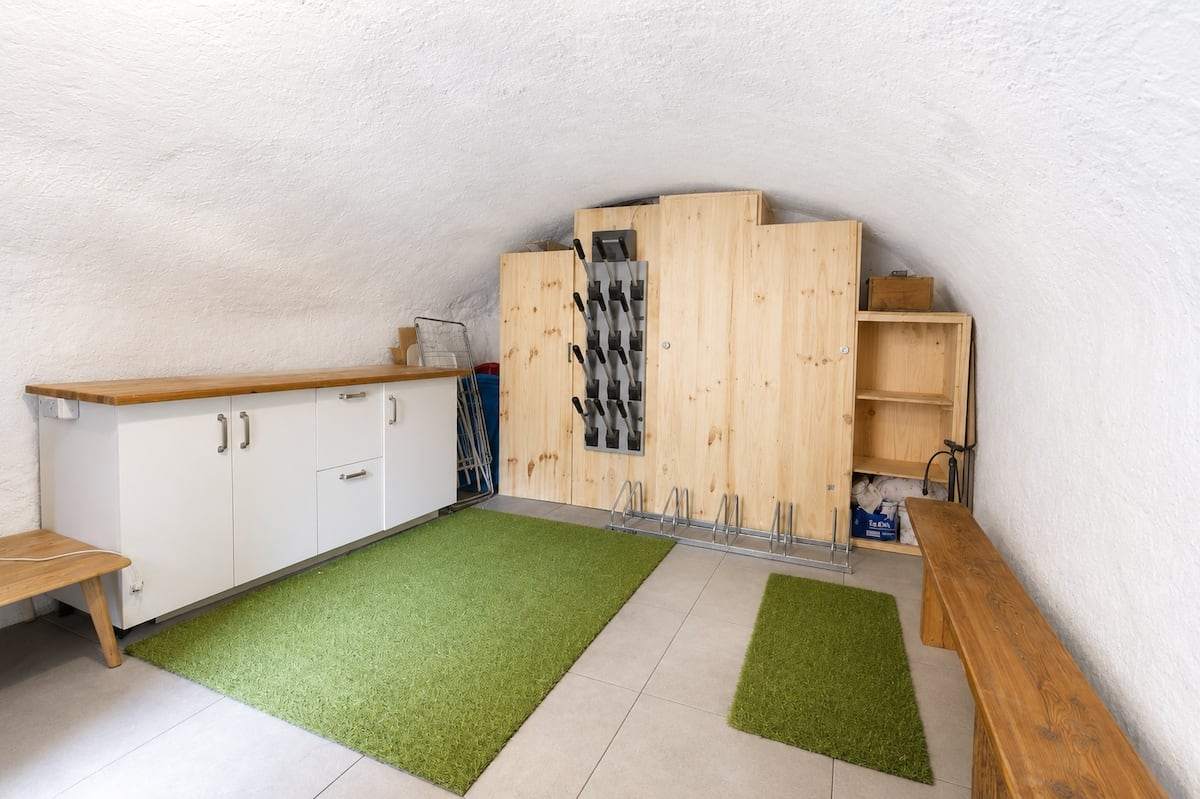 Local privé sous voûte avec sèche-chaussures, râtelier à vélos, plan de travail et banc