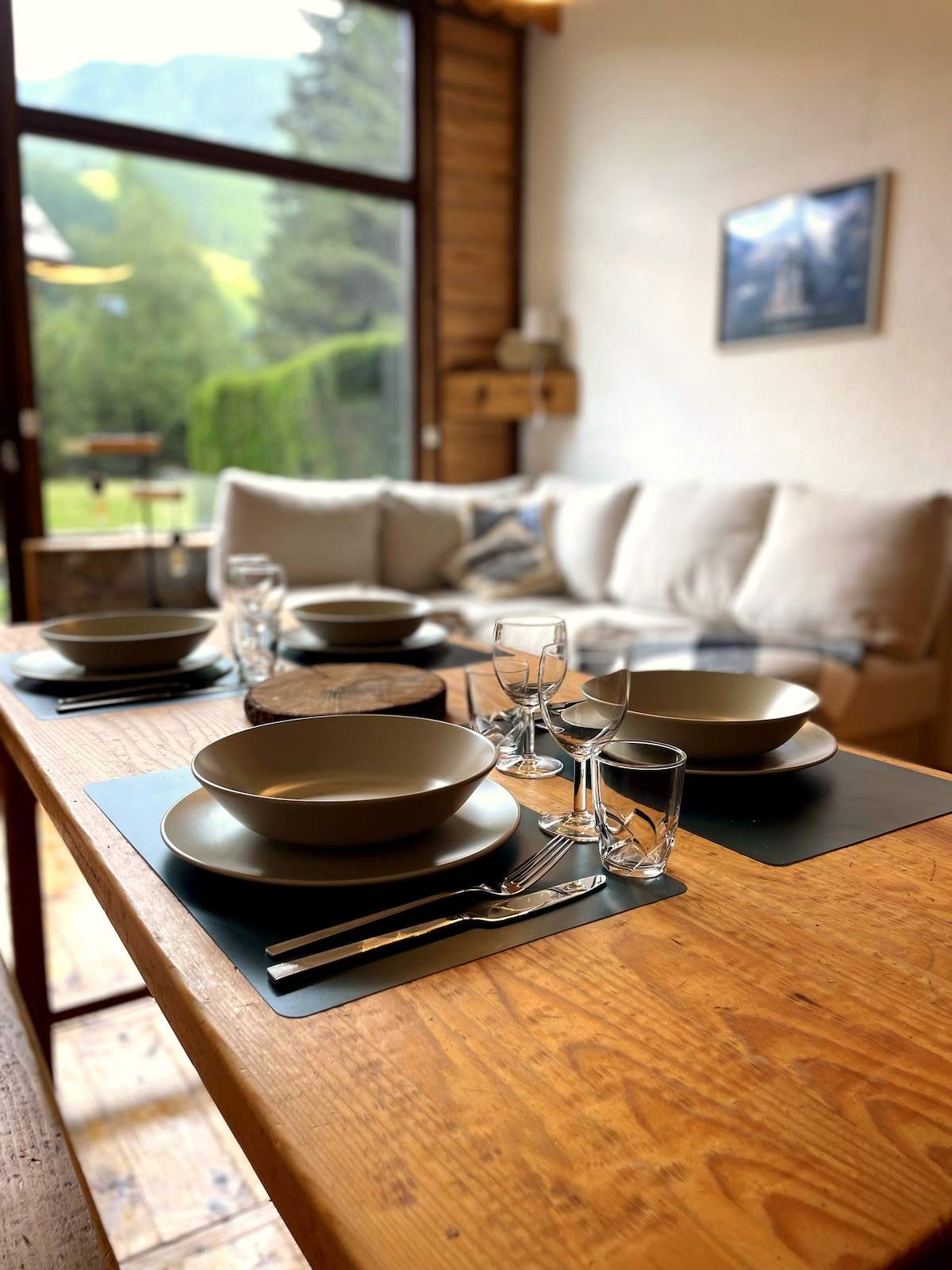 Table dressée face à la baie vitrée de l'appartement à Serre Chevalier, vaisselle kaki et vue sur la montagne